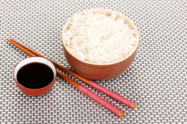 Cuenco de arroz y palillos en estera gris — Foto de Stock