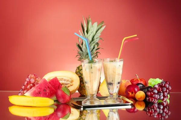 Milk shakes with fruit on red background close-up — Stock Photo, Image