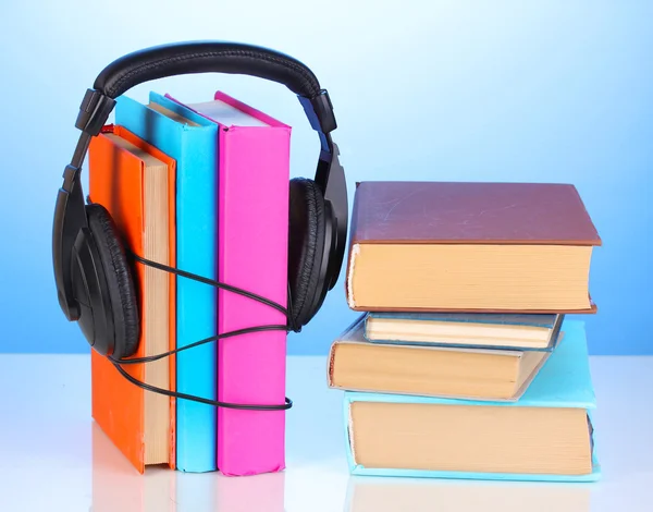 Kopfhörer auf Büchern auf blauem Hintergrund — Stockfoto