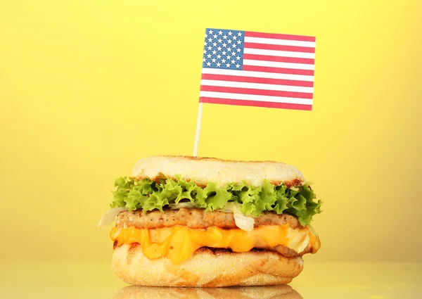 Tasty sandwich with american flag, on yellow background — Stock Photo, Image