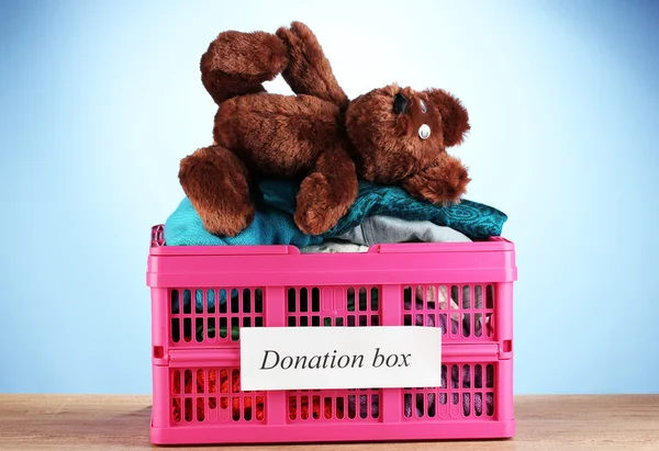 Donatie box met kleding op blauwe achtergrond close-up — Stockfoto
