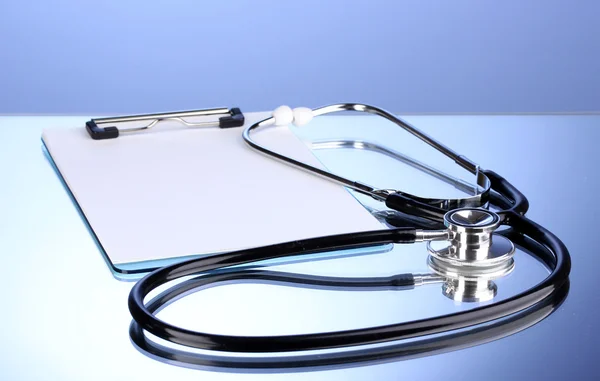 Medische stethoscoop en Klembord op blauwe achtergrond — Stockfoto