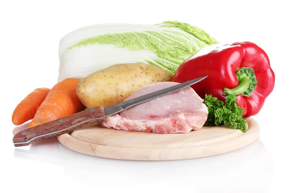Свежие овощи со свиным стейком на разделочной доске изолированы на белом — стоковое фото