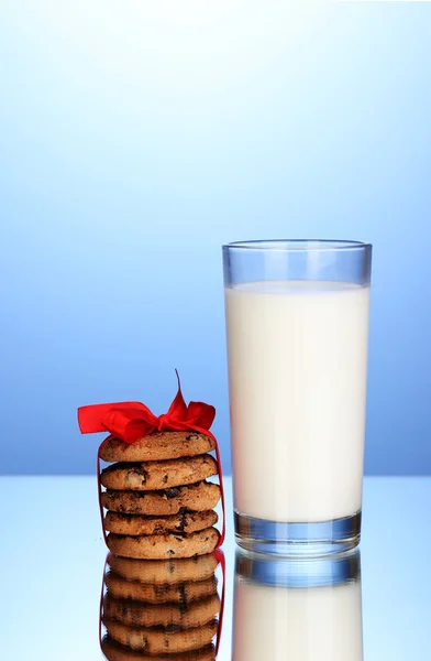 Glas melk en koekjes op blauwe achtergrond — Stockfoto