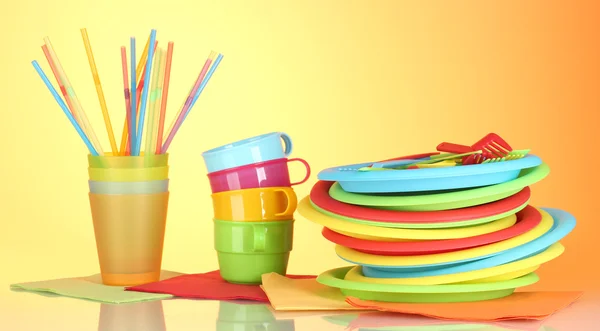Яркая пластиковая одноразовая посуда на красочном фоне — стоковое фото
