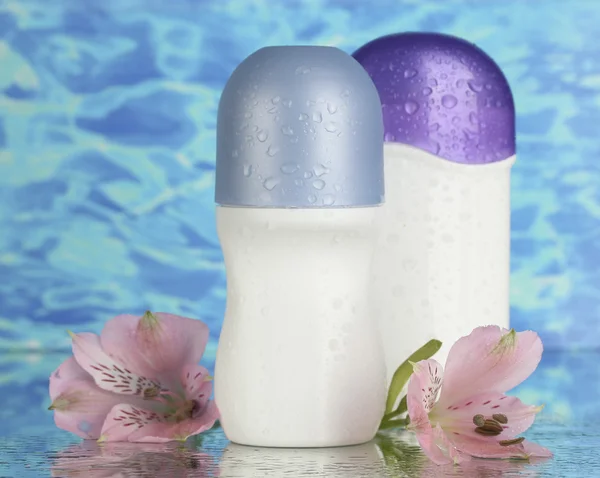 Desodorantes con flores sobre fondo azul marino — Foto de Stock