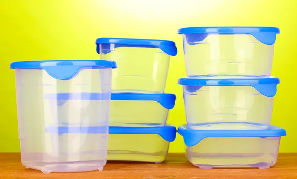 Пластиковые контейнеры для еды на деревянном столе на зеленом фоне — стоковое фото