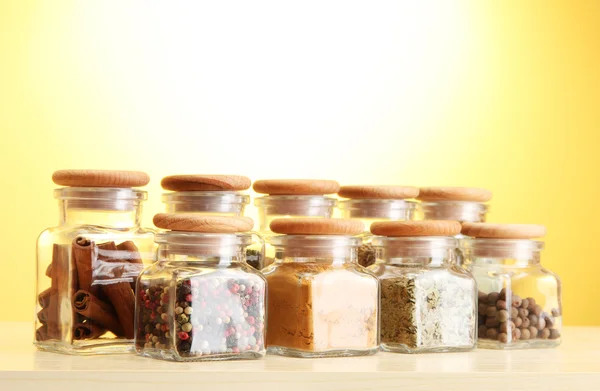 Powder spices in glass jars on yellow background — Stock Photo, Image