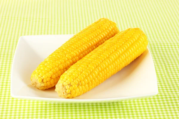 A zöld asztalterítő fehér tányérra főtt kukorica — Stock Fotó