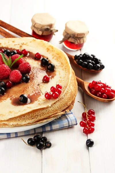 Delicious pancakes with berries and jam on plate on wooden table — Stock Photo, Image