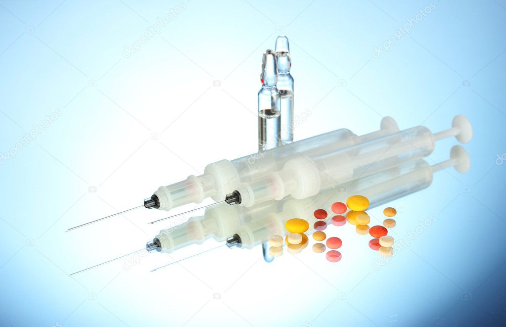 Syringes monovet, ampoules and pills on blue background
