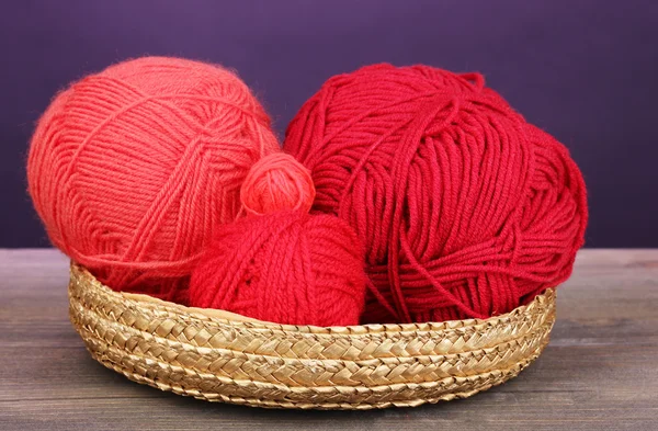 紫色の背景に木製のテーブルの [バスケットに赤の編物展糸 — ストック写真