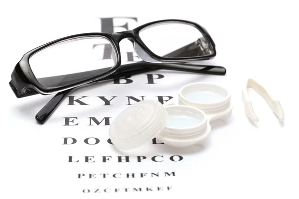 Brýle, kontaktní čočky v nádobách a pinzety na pozadí snellen oko grafu — Stock fotografie