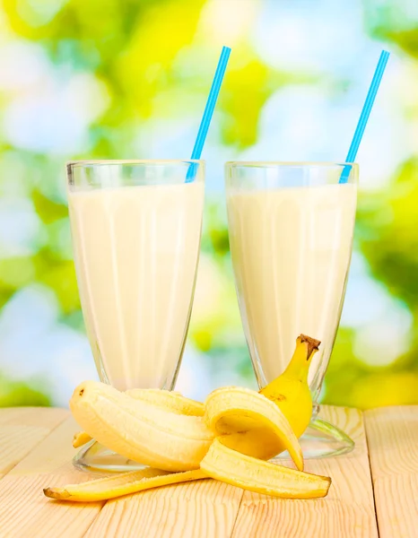 Banana milk shakes on wooden table on bright background — Stock Photo, Image