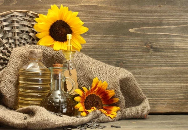 Öl in Flaschen, Sonnenblumen und Samen, auf Holzgrund — Stockfoto