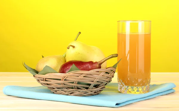 Pear juice with pears on wooden table on yellow background
