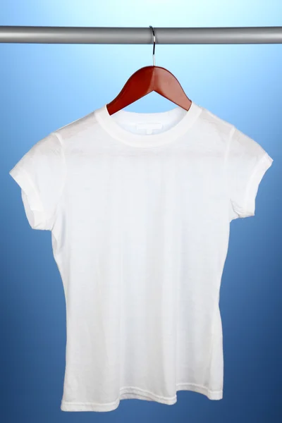 Біла футболка на вішалці на синьому фоні — стокове фото