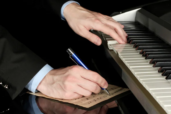 Człowiek ręce, gra na fortepianie i pisze na parer notatek — Zdjęcie stockowe