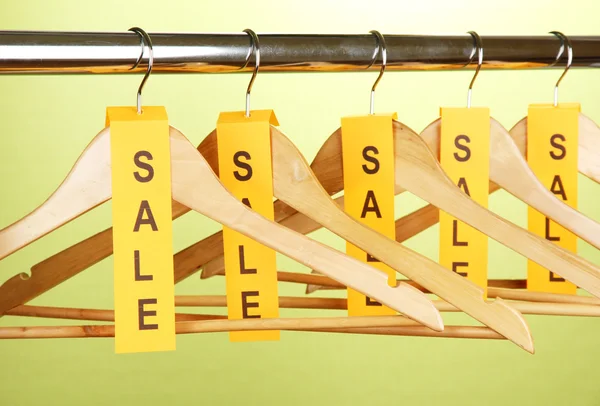 Деревянные вешалки для одежды в качестве символа продажи на зеленом фоне — стоковое фото