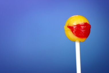 Sweet and tasty lollipop on bright blue background close-up clipart