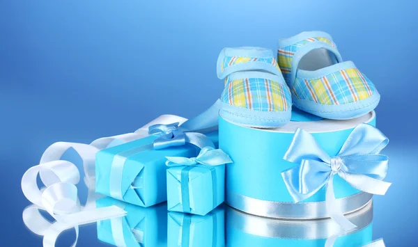Belos presentes e botas do bebê no fundo azul — Fotografia de Stock