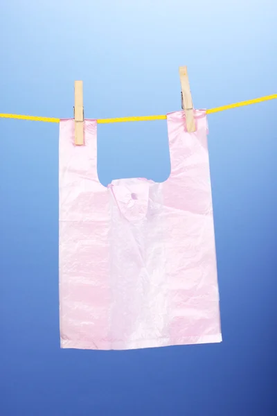 Celofánové tašku visí na laně na modrém pozadí — Stock fotografie
