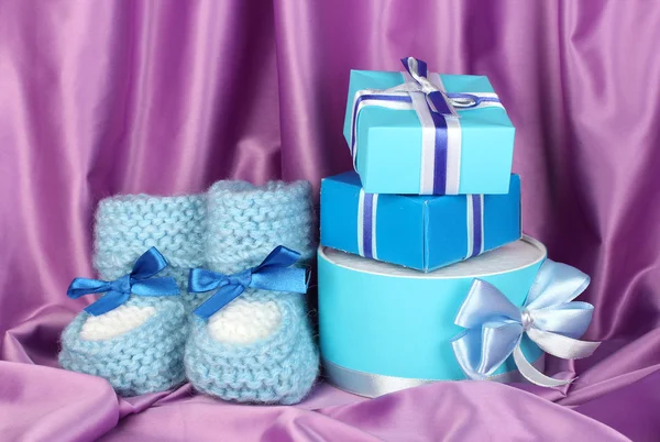 Blue baby boots and gifts on silk background — Stock Photo, Image