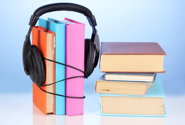 Kopfhörer auf Büchern auf blauem Hintergrund — Stockfoto