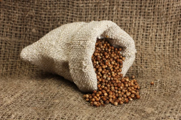 Koriander zaden in zak op doek achtergrond close-up — Stockfoto