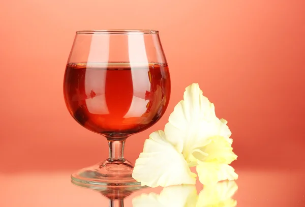 Glas met cocktail en gladiolen bud op rode achtergrond close-up — Stockfoto