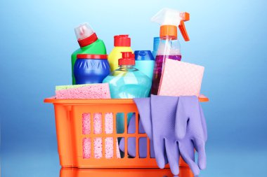 Basket with cleaning items on blue background clipart