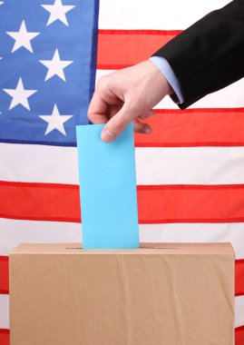 Hand with voting ballot and box on Flag of USA clipart