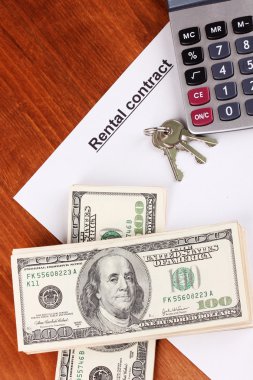 Rental contract with dollars on wooden background close-up clipart