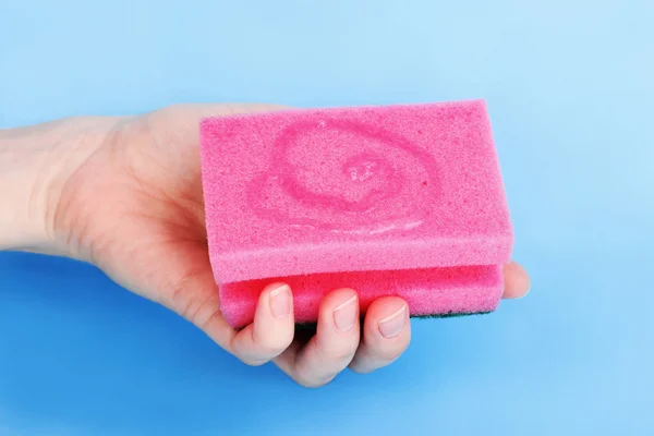 Esponja en mano con detergente sobre fondo azul — Foto de Stock