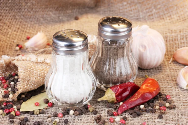 Sůl a pepř mlýny a koření na pytlovina pozadí — Stock fotografie