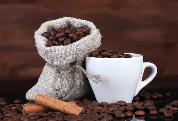 Sammansättningen av canvas säck och koppen med kaffe bönor isolerad på trä — Stockfoto
