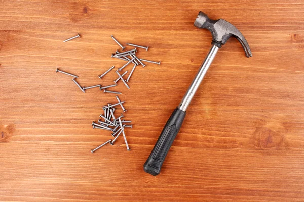 Martillo y clavos de metal sobre fondo de madera — Foto de Stock