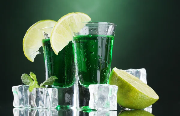 Due bicchieri di assenzio, lime e ghiaccio su fondo verde — Foto Stock