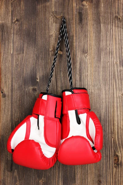 Gants de boxe rouge suspendus sur fond en bois — Photo
