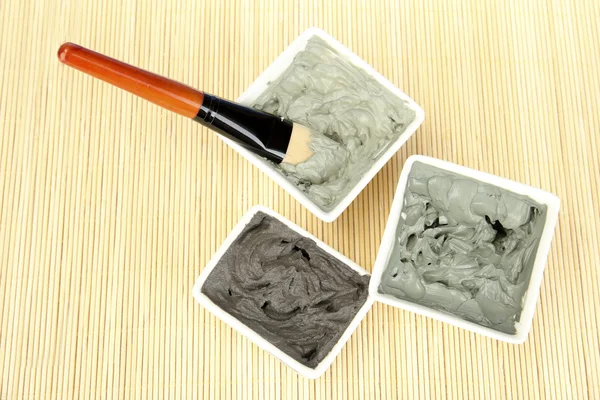 Cosmetic clay for spa treatments on straw background close-up