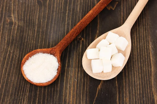 Azúcar blanco en cucharas sobre fondo de madera — Foto de Stock