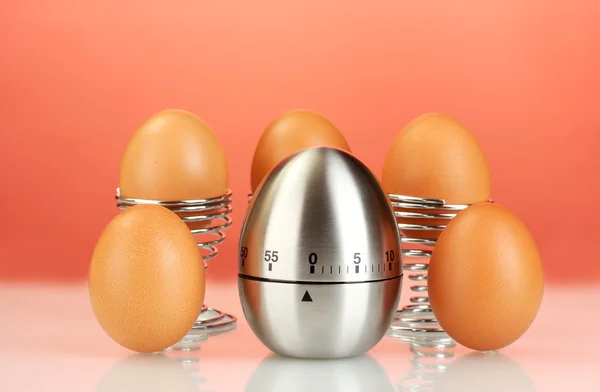 Temporizador de ovos e ovos no fundo vermelho — Fotografia de Stock
