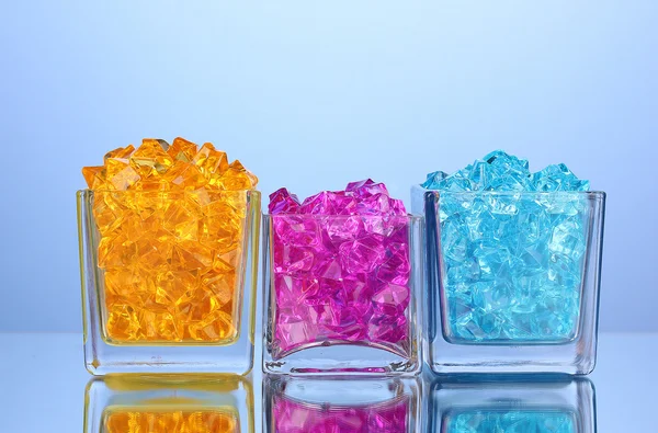 A glasses with colorful decorative stones on blue background close-up — Stock Photo, Image