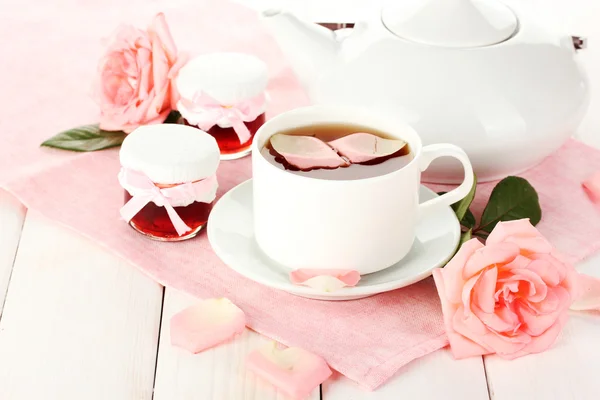 Theepot en kopje thee met rozen en jam op witte houten tafel — Stockfoto