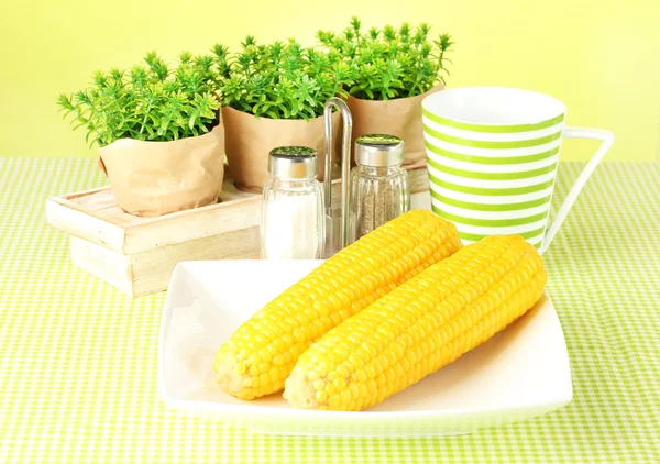 Gekochter Mais und Blumen auf grünem Hintergrund — Stockfoto