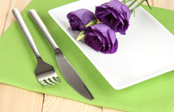 Tableware with flower on bright napkin close-up