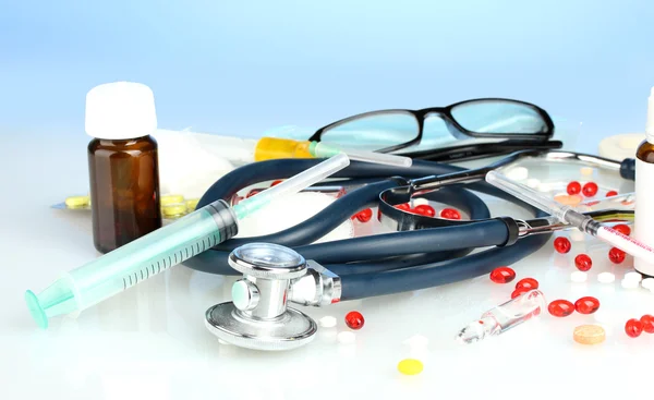 Medicamentos e um estetoscópio em um fundo azul close-up — Fotografia de Stock