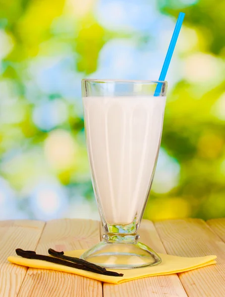 Frullato di latte alla vaniglia su tavolo di legno su sfondo luminoso — Foto Stock