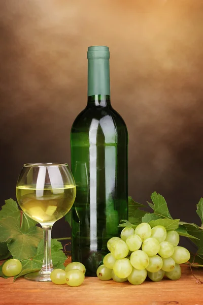 Bottle of great wine with glass on wooden table on brown background — Stock Photo, Image