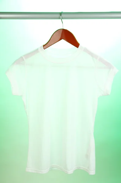 Weißes T-Shirt auf Kleiderbügel auf grünem Hintergrund — Stockfoto